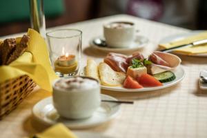 una mesa con platos de comida y tazas de café en Hotel Obermayr en Ebenau