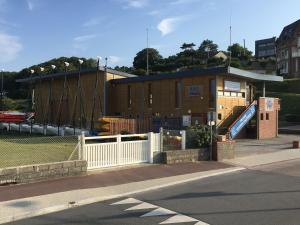 um edifício com escorrega em frente a um parque infantil em Les Mouettes, à moins de 50 Métres de la plage em Veulettes-sur-Mer