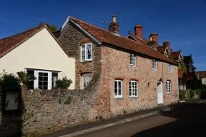 una vecchia casa di mattoni con un muro di pietra di Middle Farm Cottage a Wells