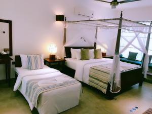 a bedroom with two beds and a canopy bed at Coza Ceylon in Mount Lavinia