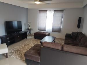 a living room with a couch and a flat screen tv at Swan Boutique Apartment in Tamuning