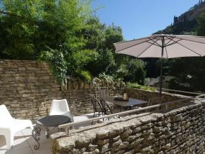 un patio con mesa, sillas y sombrilla en La Calade, maison de village, en Gordes