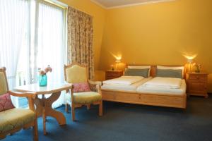 Schlafzimmer mit einem Bett, einem Tisch und Stühlen in der Unterkunft Hotel am Südwäldchen in Westerland