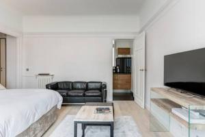 um quarto com uma cama, um sofá e uma televisão em Appartement Champs Elysées em Paris