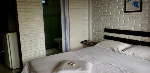 1 cama en un dormitorio con una pared de ladrillo blanco en Pousada na Montanha en Domingos Martins