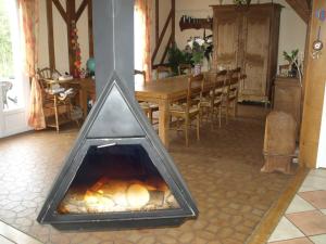 a fireplace in a dining room with a table at La Risloise in Corneville-sur-Risle