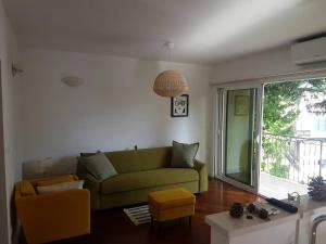 a living room with a green couch and a window at Bright Central Apartman in Tivat