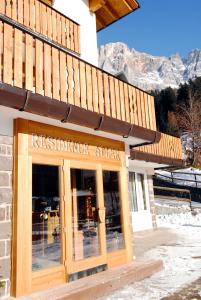 un restaurant avec un panneau à l'avant d'un bâtiment dans l'établissement Residence Adler, à San Martino di Castrozza