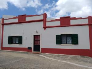 ein rot-weißes Gebäude mit grünen Fensterläden in der Unterkunft Casa Gomikika in São Brás de Alportel