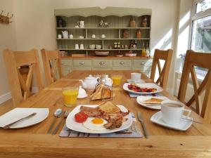 a wooden table with breakfast foods and drinks on it at Willow House B&B in West Wittering