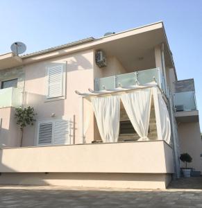 Cette maison blanche dispose d'un balcon avec un rideau blanc. dans l'établissement Apartment Josip 2, à Tribunj