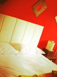 a bedroom with a white bed with a red wall at B&B PORTA APPIA in Imola