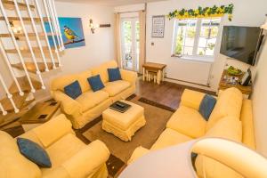 a living room with yellow couches and a tv at Swallows Nest - Covehurst Bay Cottage in Hastings