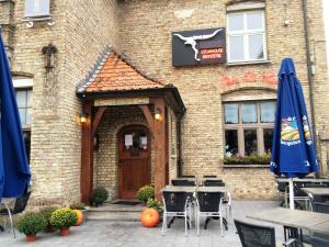 a brick building with an entrance with tables and umbrellas at Vakantiehuis Loft André in Leke