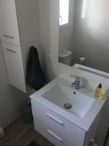 a white bathroom with a sink and a mirror at Cosy's'Plage in Kerderff