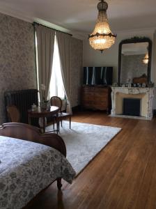 een woonkamer met een bed, een tafel en een spiegel bij L'hostellerie du chateau in Mesnil-Saint-Nicaise