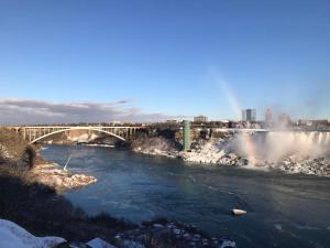 eine Brücke über einen Fluss mit einem Wasserfall in der Unterkunft Niagara Vacation Homes Canada in Niagara Falls