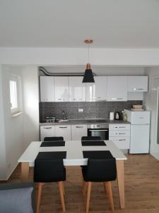 a kitchen with a white table and black chairs at Apartmani Marija in Baška Voda