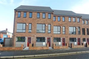 a brick building with red doors on a street at Denny Guests House / Green Lane in Liverpool