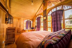 a bedroom with a bed in a room with windows at Lake Front Cabin in Santa Cruz La Laguna