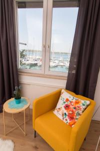 a yellow chair and a table in a room with windows at Harbour-Apartment with sea view and parking spot in Pula