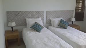 马勒勒角Element Bay Lux Beach Apartment的一间卧室配有两张带枕头和两张桌子的床。 更多21张照片