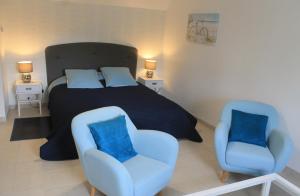 a bedroom with a bed and two blue chairs at Domaine du Jardin " Chambres d'hôtes " in Saint-Jean-de-la-Haize