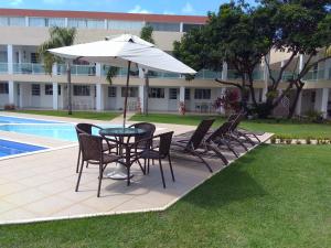 a table and chairs with an umbrella next to a pool at Flat 123 Bella Lunna in Guarajuba