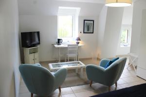 een woonkamer met stoelen en een tafel en een televisie bij Domaine du Jardin " Chambres d'hôtes " in Saint-Jean-de-la-Haize