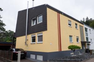 a yellow and black building with a black roof at Sehr schöne Ferienwohnung am Starkenbrunnen in Ruppertsweiler