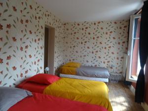 Cette chambre comprend 3 lits avec des couvertures colorées. dans l'établissement Gîte "La Maison", à Revin