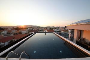 a swimming pool on the roof of a house with the sunset at Hotel Scala d'Oro in Vodice
