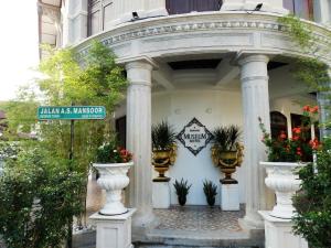 an archway with potted plants and a sign on a building at Museum Hotel in George Town