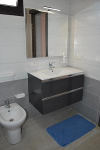 een badkamer met een wastafel, een toilet en een spiegel bij Narciso in Portopalo