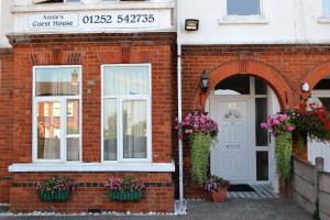 a brick building with two windows and a door with flowers at Annie's Guest House in Farnborough