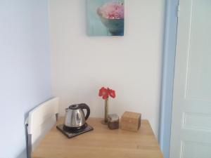 a table with a tea kettle and a flower on it at Chambre Saint-Sauveur in Les Andelys
