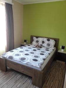 a large bed in a bedroom with a green wall at Kerékvár apartman Gyula in Gyula