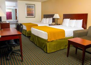 a hotel room with two beds and a desk at Budget Inn & Suites Guymon in Guymon