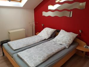 two beds in a room with a red wall at Höllenbergblick in Spirkelbach