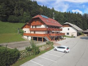 une voiture blanche garée devant un grand bâtiment dans l'établissement Guest house Pr Ambružarju & Apartments, à Cerklje na Gorenjskem