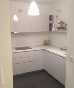 una cocina blanca con armarios blancos y fregadero en Ferienwohnung am Zwinger en Dresden