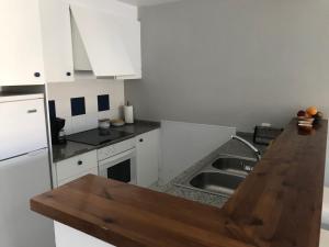 パルスにあるApartamento en Playa de Pals Costa Bravaのキッチン(白いキャビネット、木製カウンタートップ付)