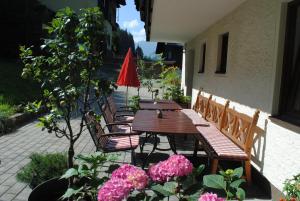 a patio with a wooden table and chairs and flowers at Naturhaus Andrea in Grossarl
