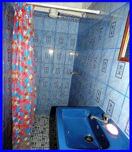 Baño azul con lavabo y cortina de ducha en Rositas Hotel, en San Juan del Sur