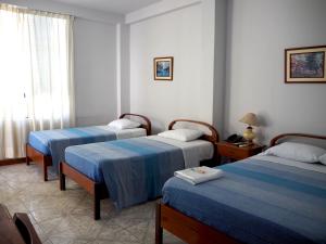 Habitación de hotel con 3 camas y ventana en Hotel Peru Amazonico, en Puerto Maldonado