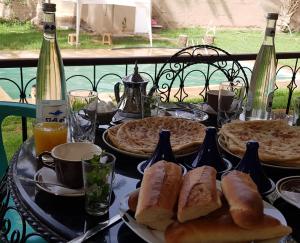 a table with two plates of bread and wine bottles at Maison d Hôte Ighrem in Goulmima