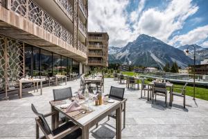 a restaurant with tables and chairs and a mountain at Valsana Hotel Arosa in Arosa