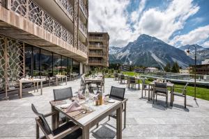 a restaurant with tables and chairs and a mountain at Valsana Hotel Arosa - Small Luxury Hotels of the World in Arosa
