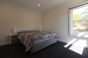 a white bedroom with a bed and a window at Leichhardt Cottages in Relbia