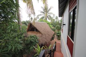 a house with a thatch roof next to a porch at Green Life Cottage in Siem Reap